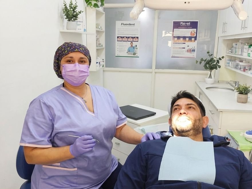 Profesional del consultorio junto al paciente en el sillón
